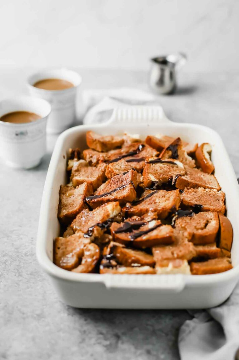 Side angle of Chocolate Caramel Gluten Free French Toast Casserole in a white baking dish.