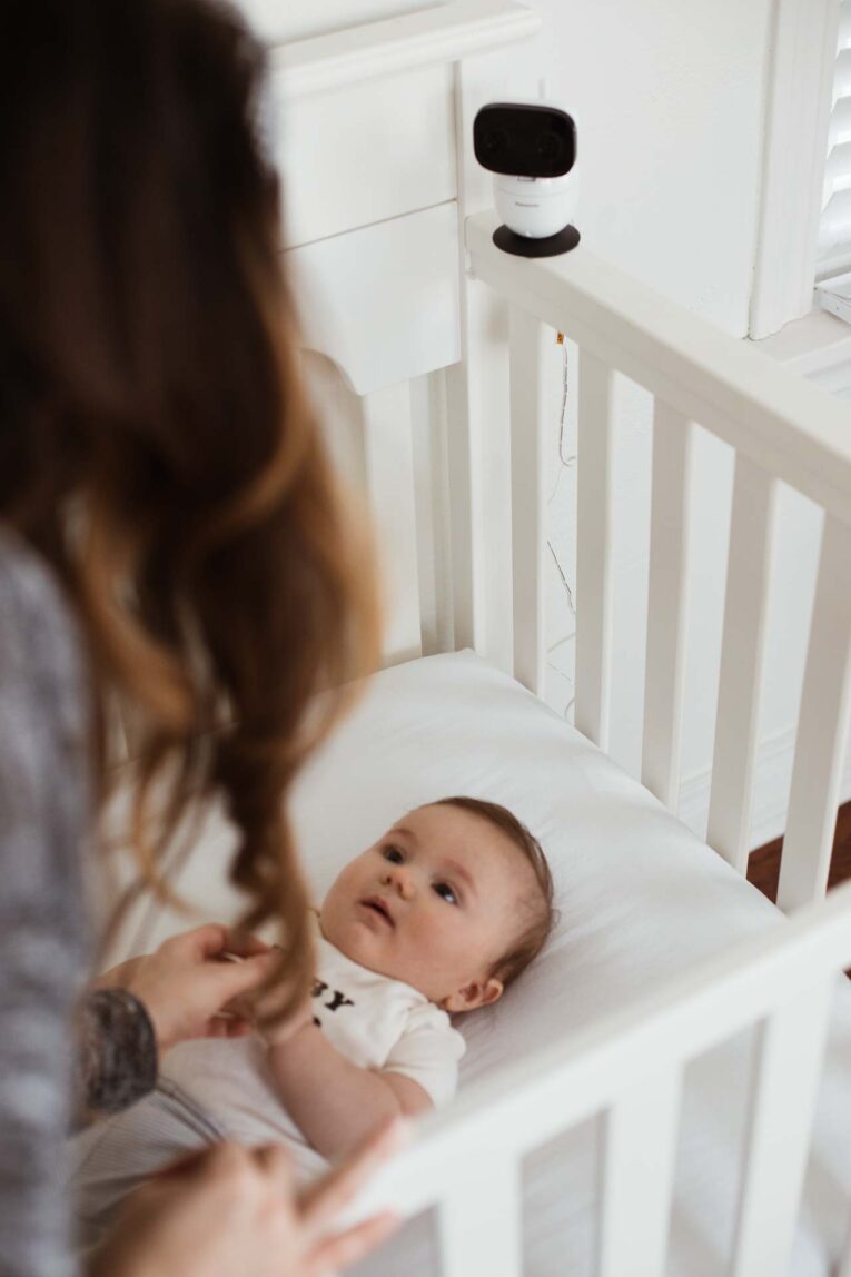 mom looking at baby laying in crib.