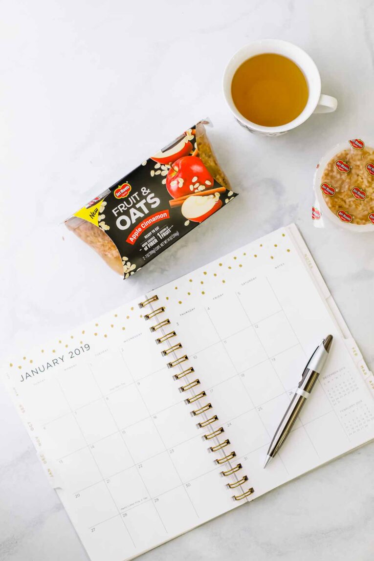 Overhead shot of Del Monte fruit and oats package with a cup of tea and a calendar.