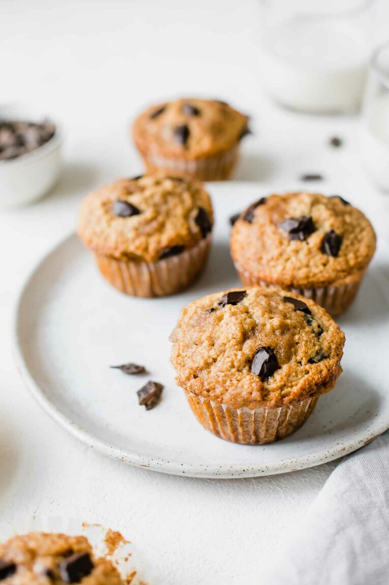 Favorite healthy banana chocolate chip oatmeal muffins on a plate with milk in the background.