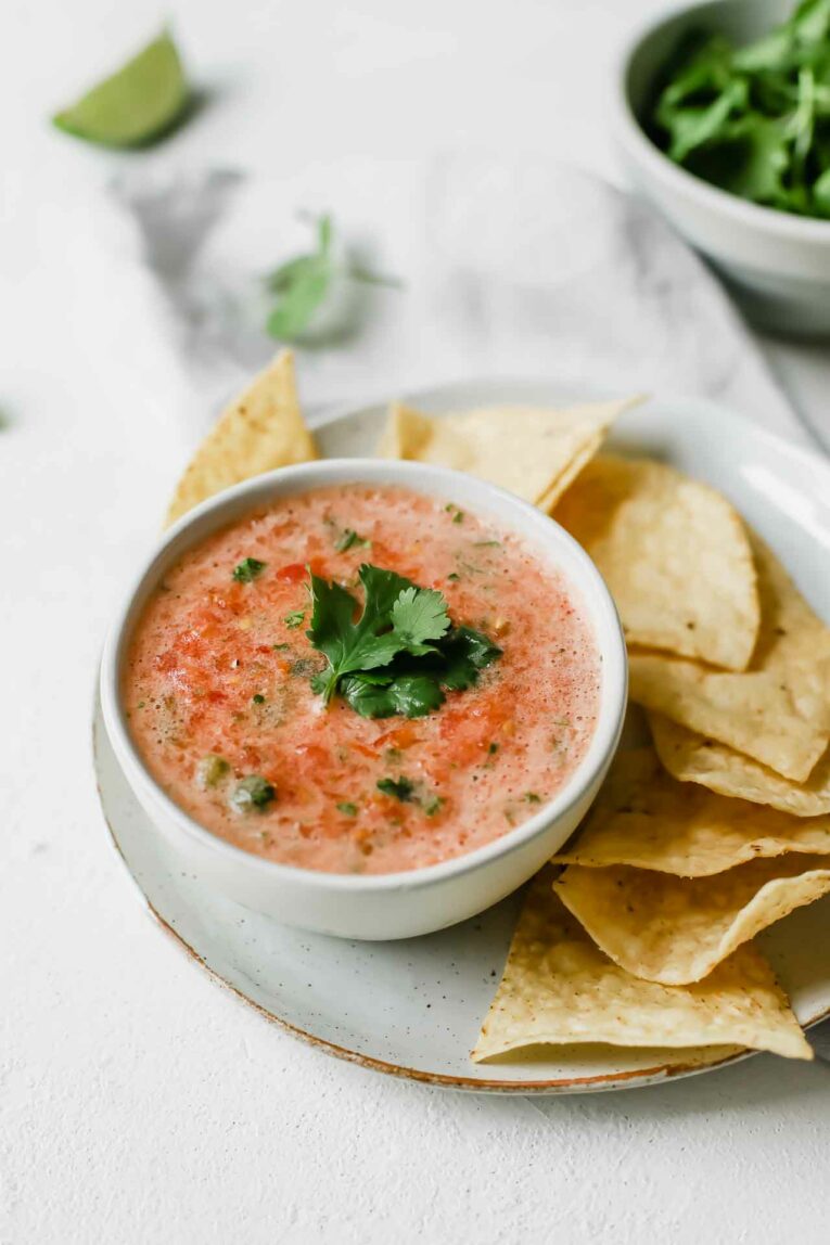 The BEST Easy Salsa Recipe made with plum tomatoes, jalapeño, and cilantro. So yummy! Close up of the best easy salsa recipe in a bowl over a plate with tortilla chips