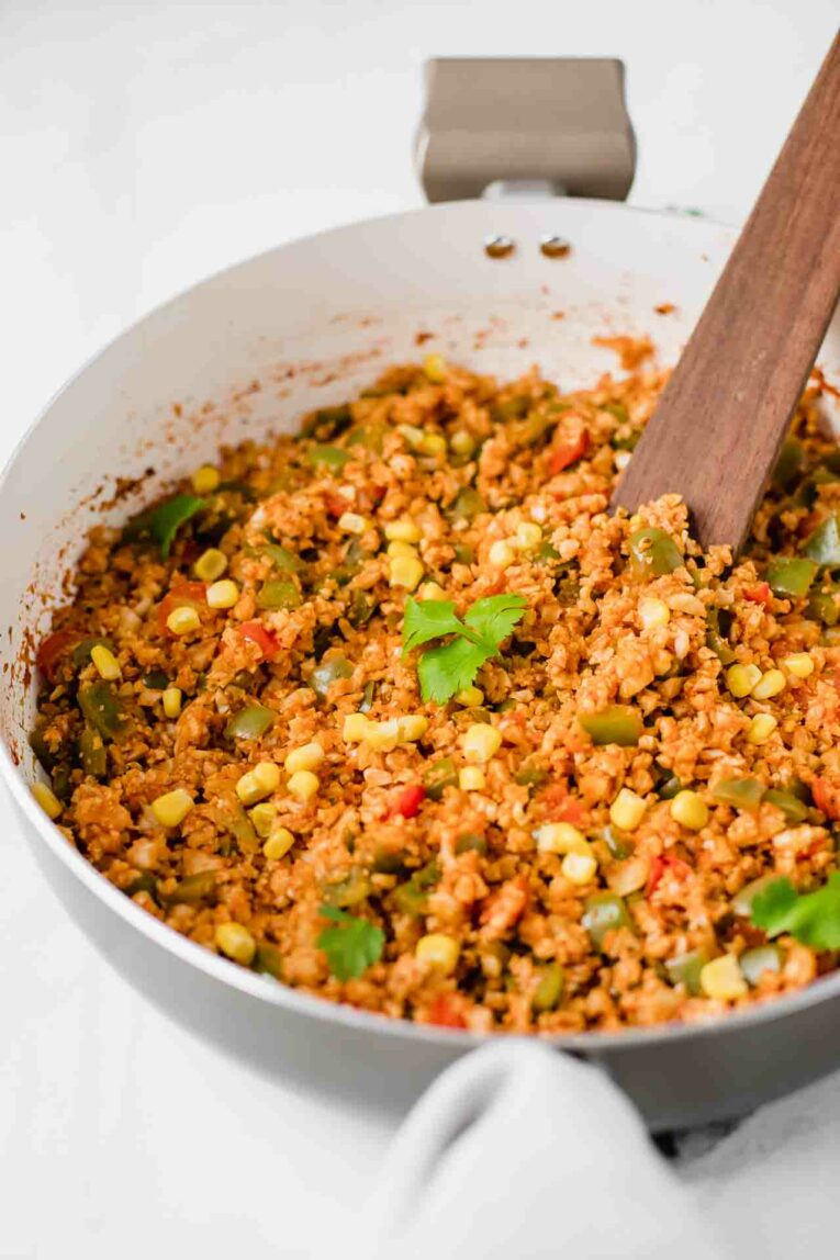 Savory, simple, and healthy. This 30-Minute Mexican Cauliflower Rice recipe is the best ever and is vegan, vegetarian, gluten-free, dairy-free, and paleo. It's perfect for dinner tonight! Angled shot of 30-Minute Mexican Cauliflower Rice in a sauce pan.