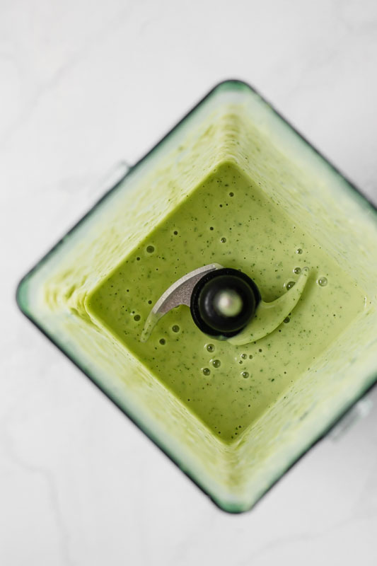 Blended green avocado smoothie in a blender.