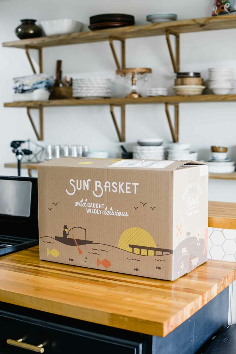 Looking for a quick and easy solution to healthy weeknight dinners? Then Sun Basket might be for you. Today, I'm sharing all about my week with Sun Basket (an honest review along with an unboxing video and a promo code)! Sun Basket box on kitchen countertop.