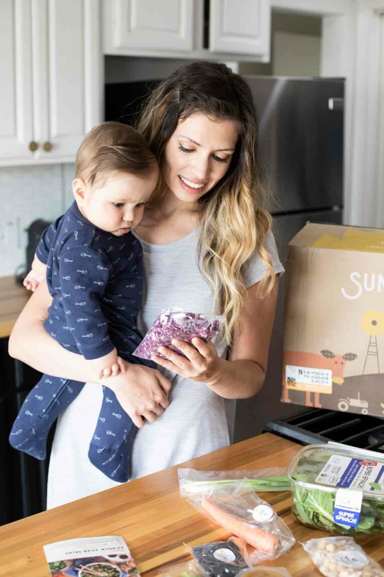 Looking for a quick and easy solution to healthy weeknight dinners? Then Sun Basket might be for you. Today, I'm sharing all about my week with Sun Basket (an honest review along with an unboxing video and a promo code)! Mother and baby making a Sun Basket recipe.