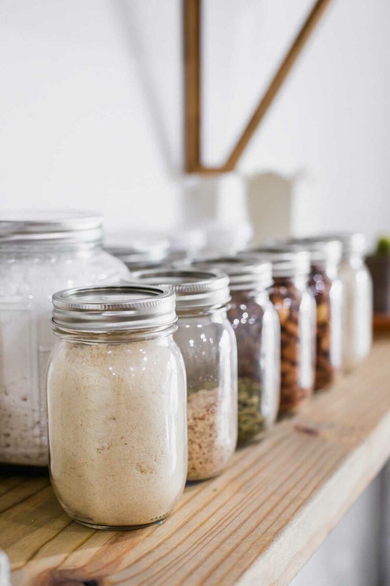 Mason jars in pantry filled with grains, nuts, and flour.