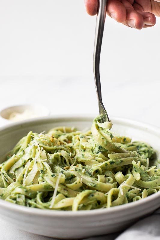 The BEST Avocado Pasta Sauce that can be made in 10-minutes or less! It's quick, easy, healthy, gluten-free, dairy-free, vegan, and delicious. Perfect for dinner tonight! Fettuccine with avocado pasta sauce in a large bowl.