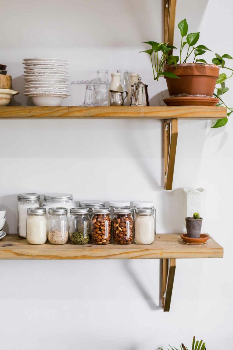 Mason jars on open shelving full of pantry ingredients.
