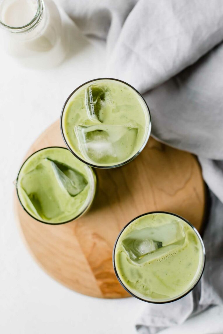 Need an afternoon pick-me-up? This 5-Minute Iced Green Tea Matcha Latte is vegan, dairy-free, loaded with antioxidants, low in sugar, and delicious! Top view of 3 Iced Green Tea Matcha Lattes in clear glasses.