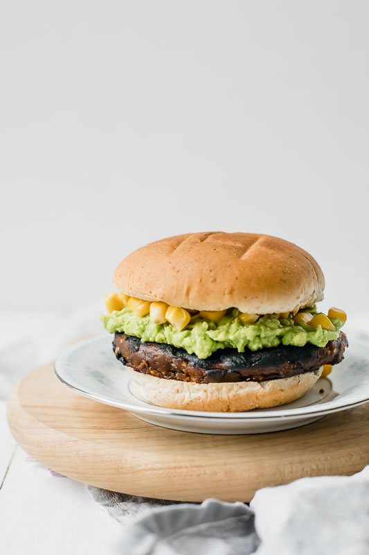 Veggie burger served on a plate sitting on a cutting board.