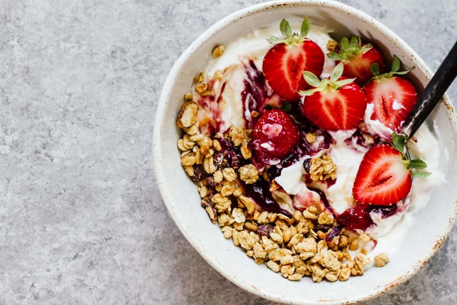 Strawberry and granola yogurt bowl with a spoon.