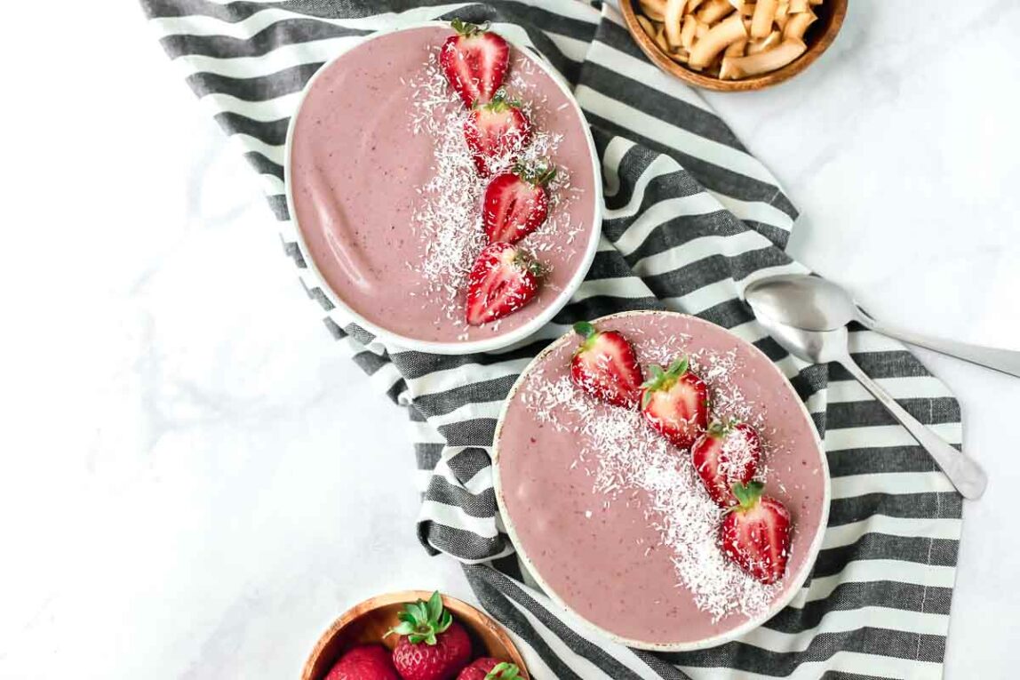 Strawberry acai smoothie bowls on a striped dish towel