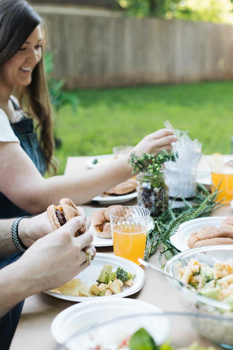 Friends eating at a picnic table for a casual summer gathering.