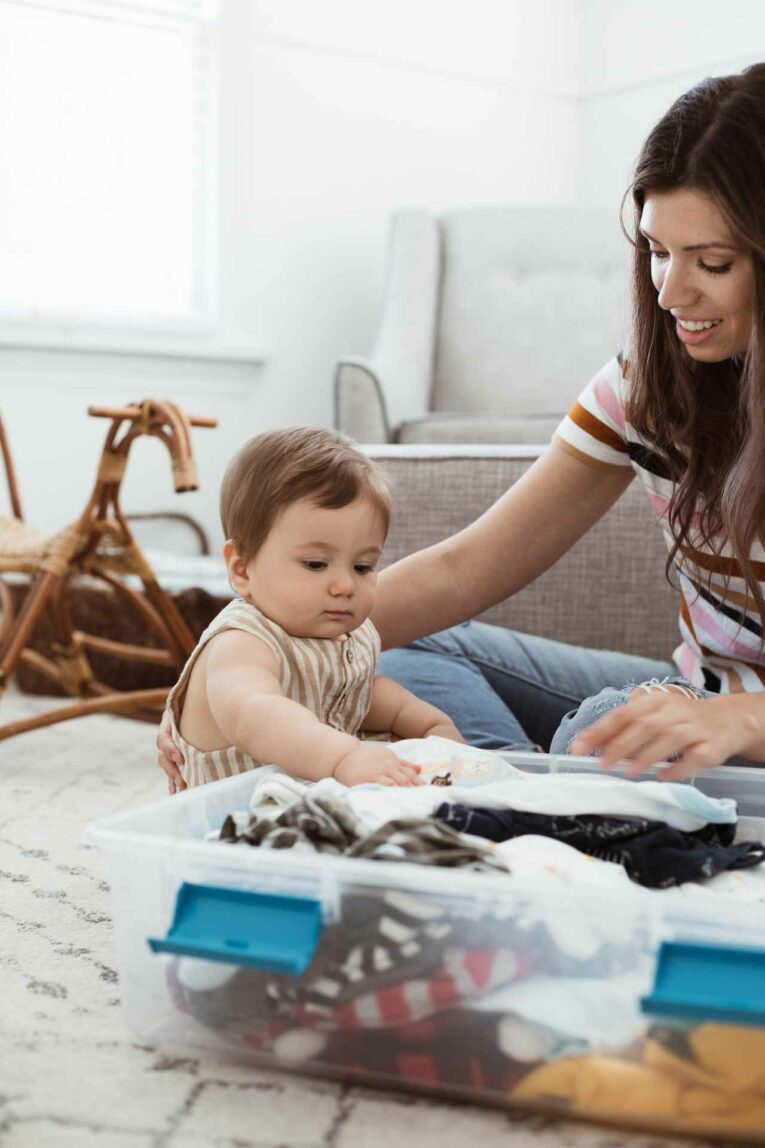 Mom and baby in nursery storing baby clothes.
