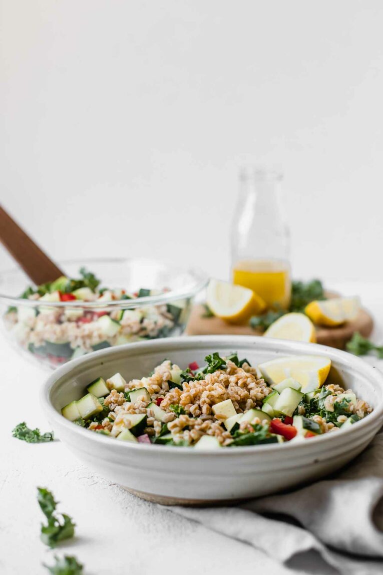 Mediterranean Farro Salad in a bowl topped with lemon vinaigrette dressing.