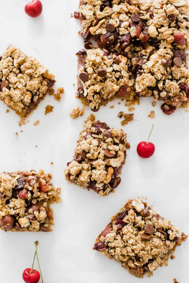 Chocolate Cherry Crumble Dessert Bars on parchment paper with fresh cherries.