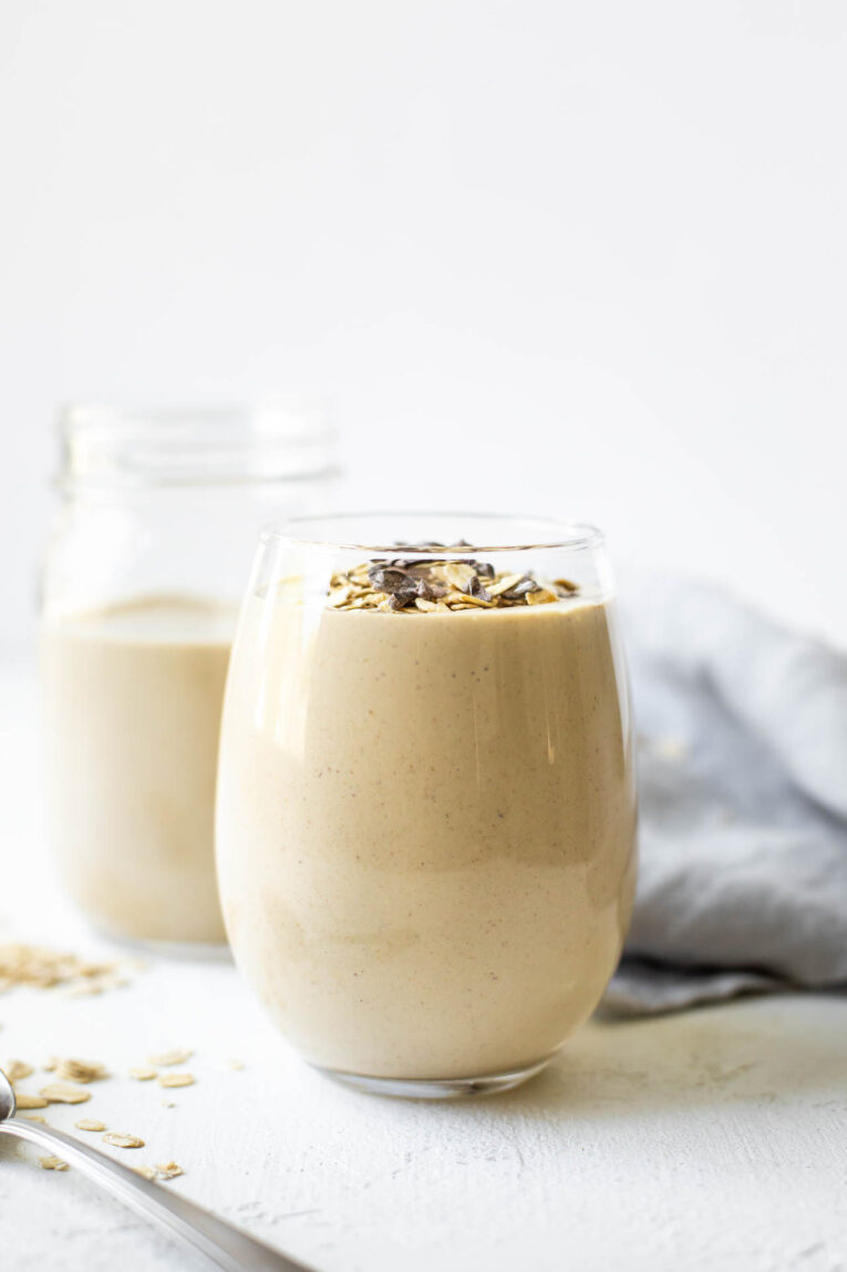 Creamy peanut butter oatmeal smoothie in a glass cup topped with granola.