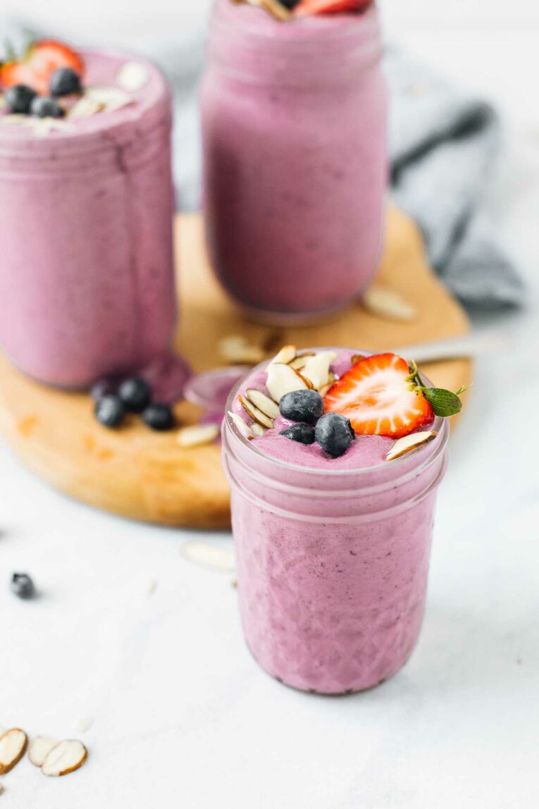 Fruit smoothie topped with blueberries, strawberries, and sliced almonds.