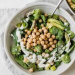 Simple green goodness chickpea salad in a white bowl with a fork.