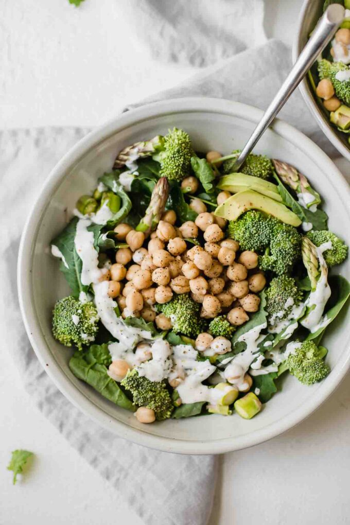 Simple green goodness chickpea salad in a white bowl with a fork.