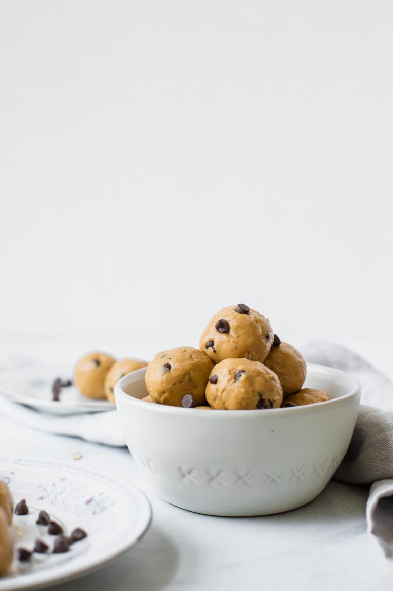 The BEST Peanut Butter Energy Balls that only take about 10 minutes to make. Keep these healthy bites on hand for easy snacking or take them on-the-go! (Vegan, vegetarian, gluten-free, dairy-free, refined sugar free) The BEST Peanut Butter Energy Balls made with peanut butter, honey, rolled oats, protein powder, and chocolate chips. Served in a white bowl.