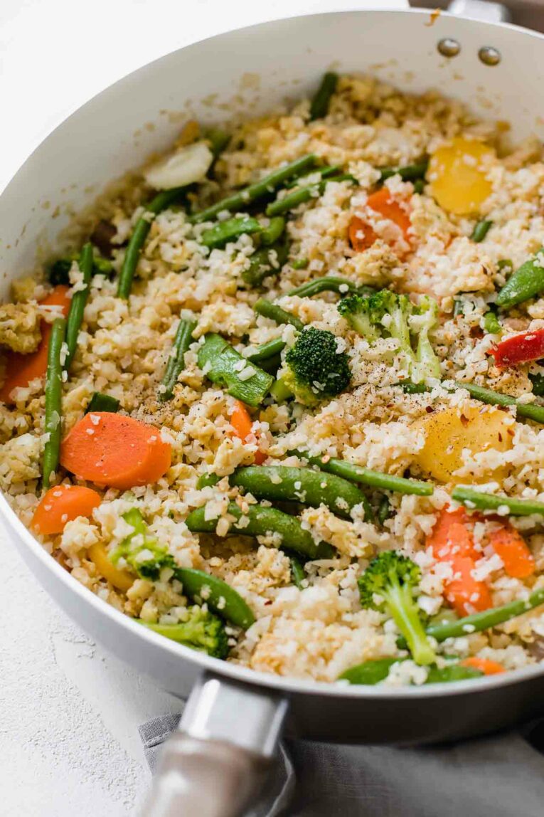 The Best Cauliflower Fried Rice that's perfect for dinner tonight! This 10-minute recipe is easy to make, gluten-free, dairy-free, vegetarian, and great for the entire family. Angle shot of the best Cauliflower Fried Rice recipe in a skillet