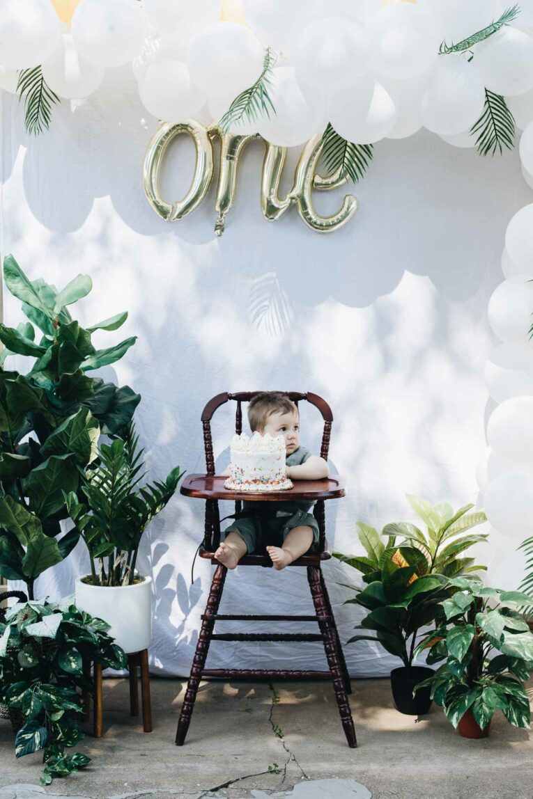 Tropical Plant First Birthday Party Baby Boy Tropical Plant First Birthday Party. Baby boy sitting with a cake.