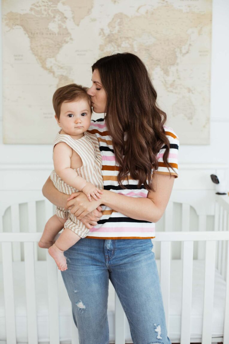 Mom kissing baby in front of crib