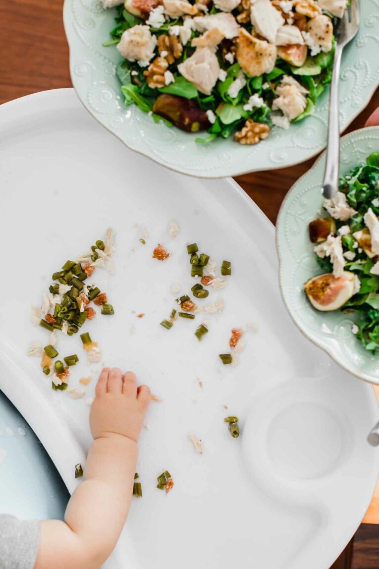 Want to get your baby started on finger foods? Here are 15 of the BEST, easiest, and simple baby led weaning recipes ideas! Baby hand grabbing Finely chopped food on a high chair