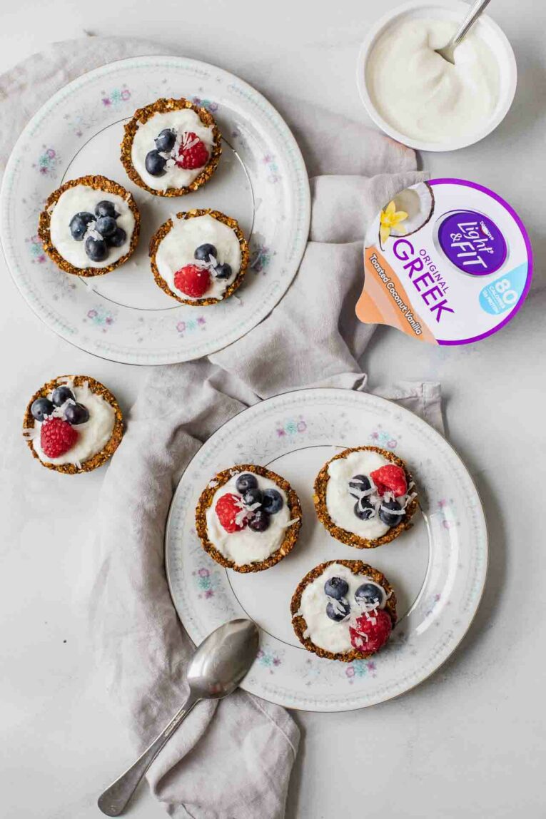 coconut vanilla breakfast yogurt cups served on two plates next to container of yogurt.