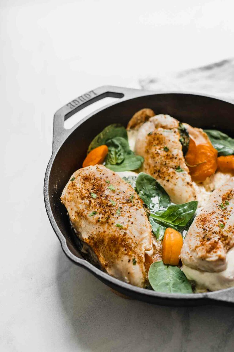 Chicken breast stuffed with apricots, mozzarella, and spinach in a skillet.