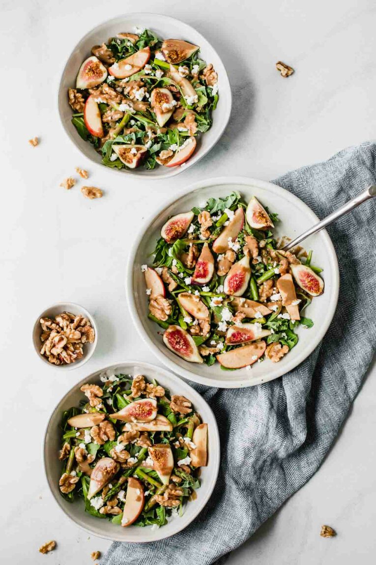 A top shot of 3 bowls of fig and goat cheese salad with a napkin underneath.
