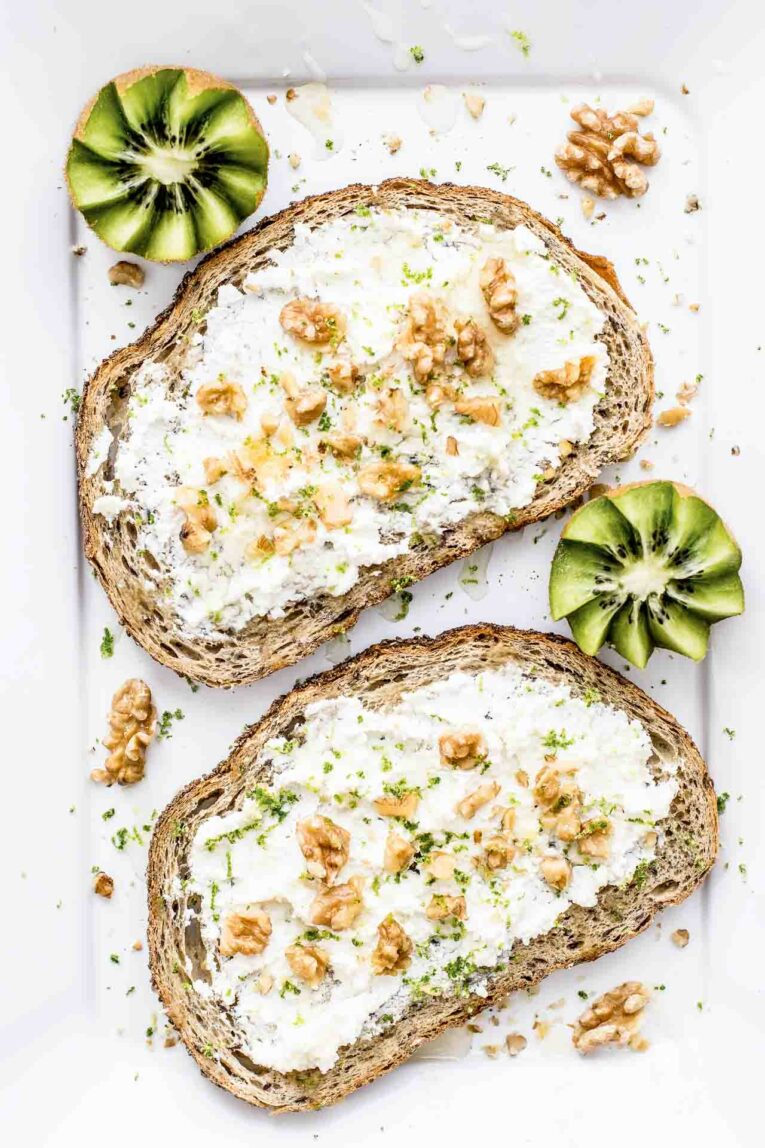 New to healthy eating? Here's how to establish healthy eating habits - and stick with them! Toast with cream cheese and walnuts on a white surface next to kiwi