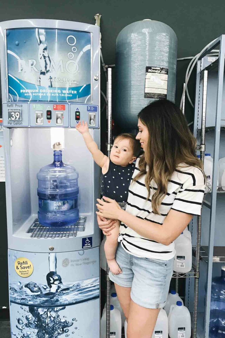 Curious to know what the best drinking water is for your baby, toddler, and entire family? Today we're sharing all about how to find the best drinking water, how to prepare formula with it, and how to implement an easy plan to keep high quality water on hand! Mom holding baby standing next to primo water.