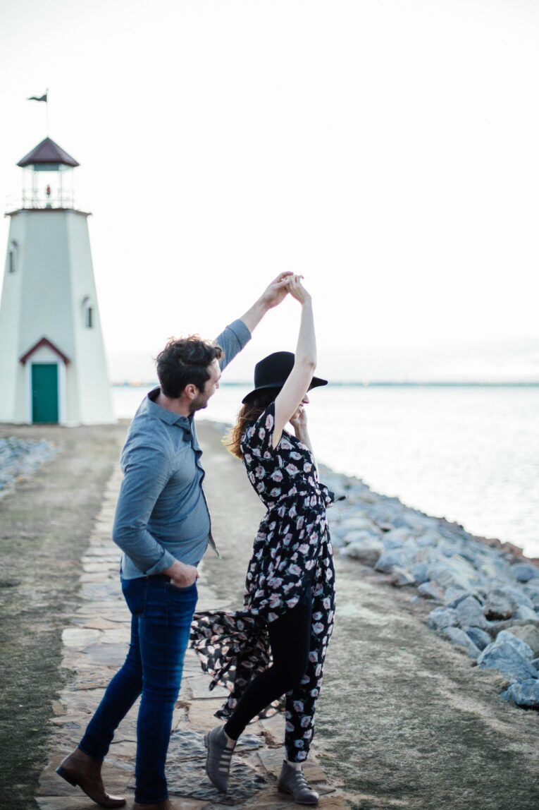 Date night in this weekend? Today, we're sharing all of the best at home date night ideas from our REAL readers! Man twirling woman outside in front of lake and small lighthouse.