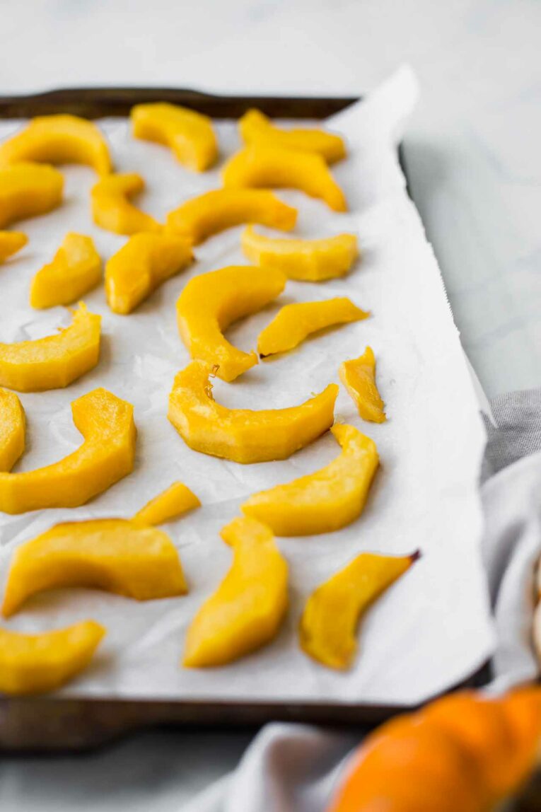 Angle shot of roasted pumpkin slices on a baking sheet.