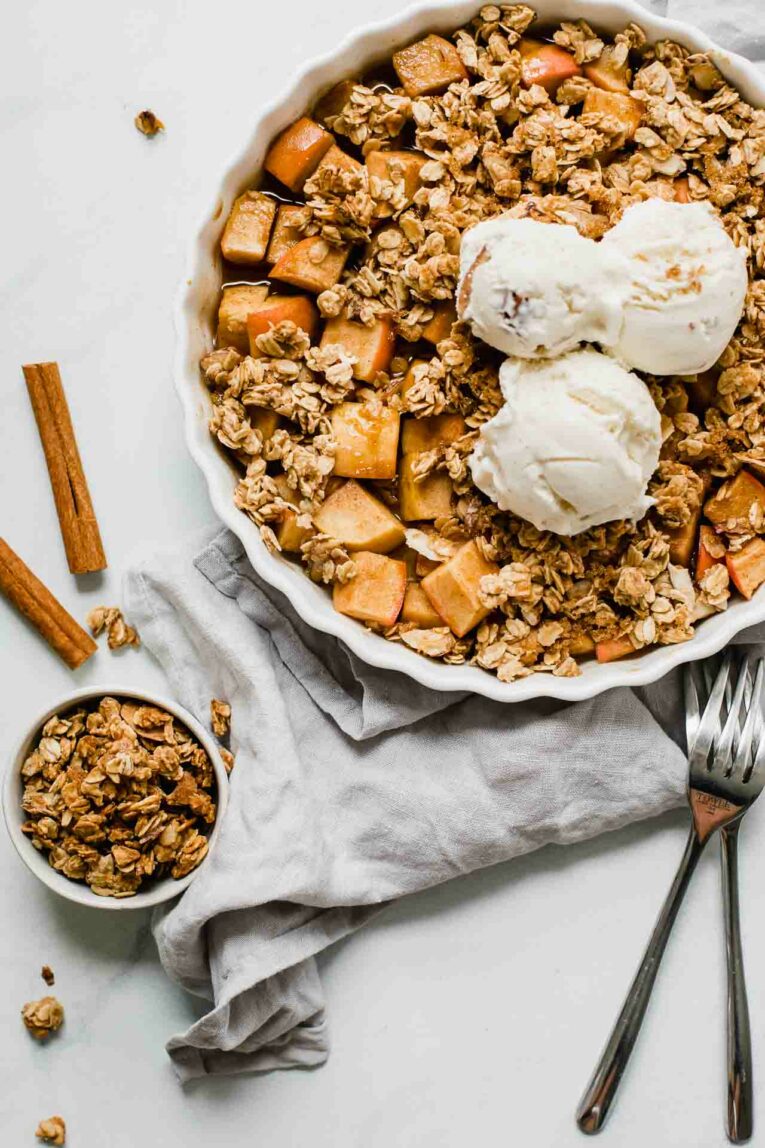 Dairy free and vegan apple crisp in a pie dish with ice cream.