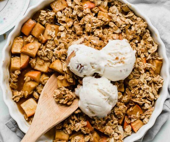 Healthy Apple Crisp in a tart dish with a wooden spoon.