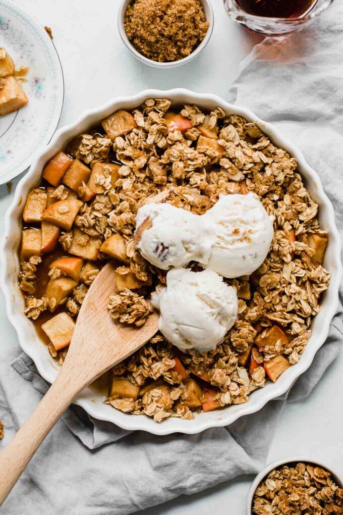Healthy Apple Crisp in a tart dish with a wooden spoon.