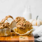 The BEST Healthy Pumpkin Muffins recipe on a cutting board with pumpkin in background.
