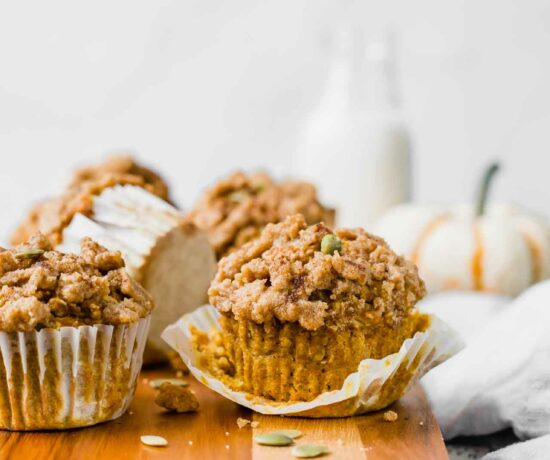 The BEST Healthy Pumpkin Muffins recipe on a cutting board with pumpkin in background.