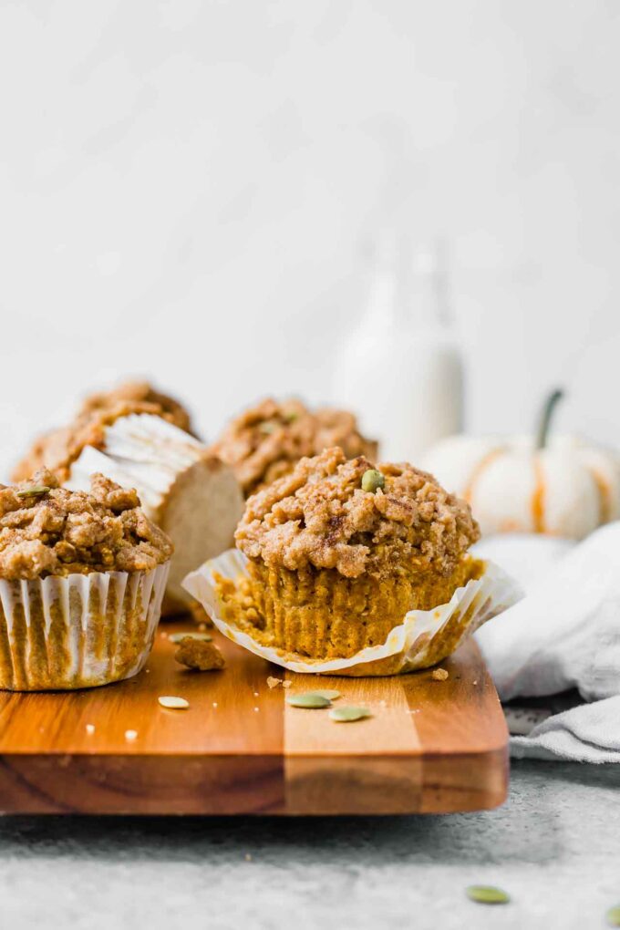 The BEST Healthy Pumpkin Muffins recipe on a cutting board with pumpkin in background.