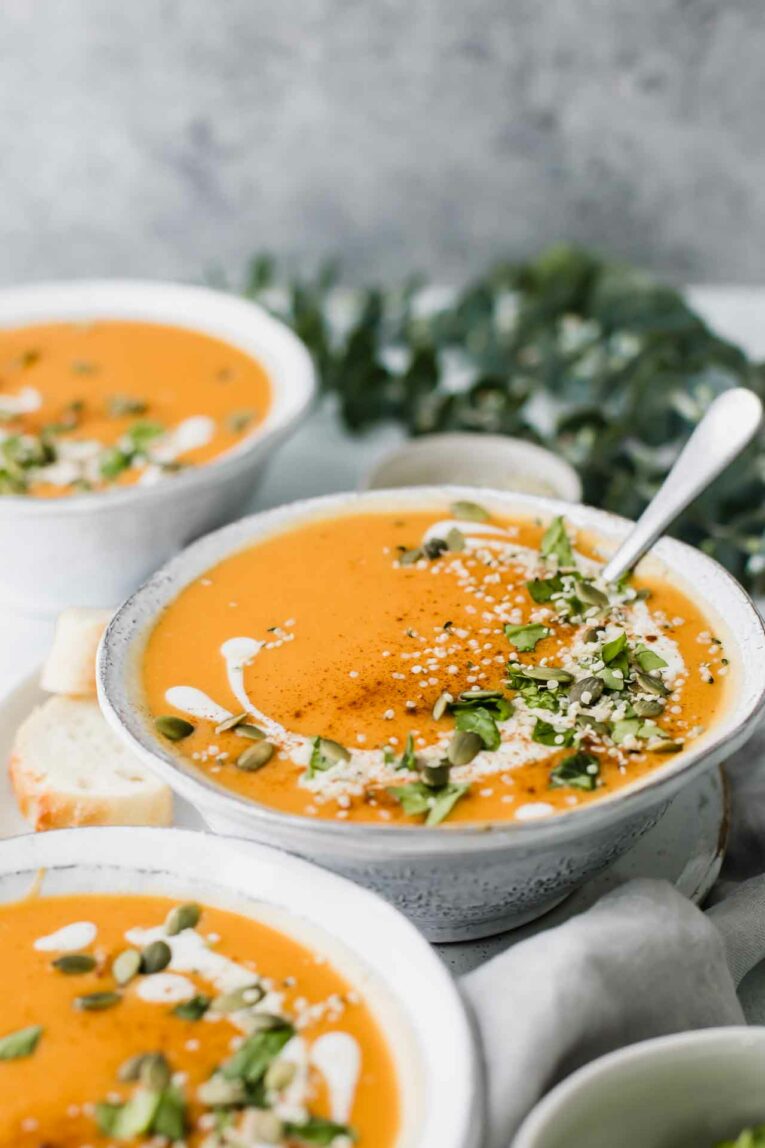 Angled shot of sweet potato soup in a white bowl with a spoon.