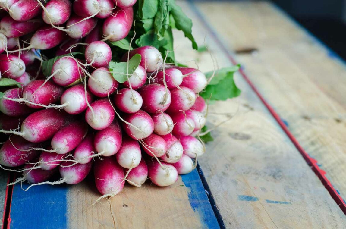 Raw Radishes with Greens on a Wood Table.