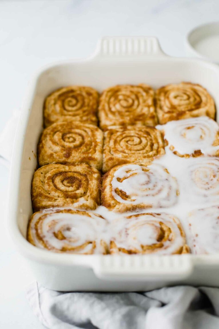 Angled shot of vegan cinnamon rolls in a baking dish.