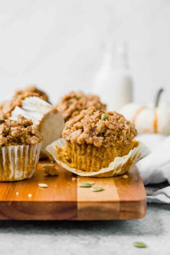 The BEST Healthy Pumpkin Muffins recipe on a cutting board with pumpkin in background.