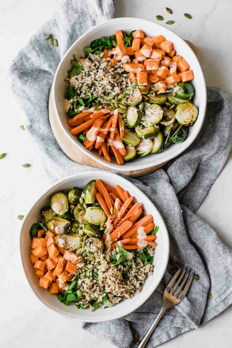 Two fall harvest bowls with roasted veggies, rice, and chopped greens.