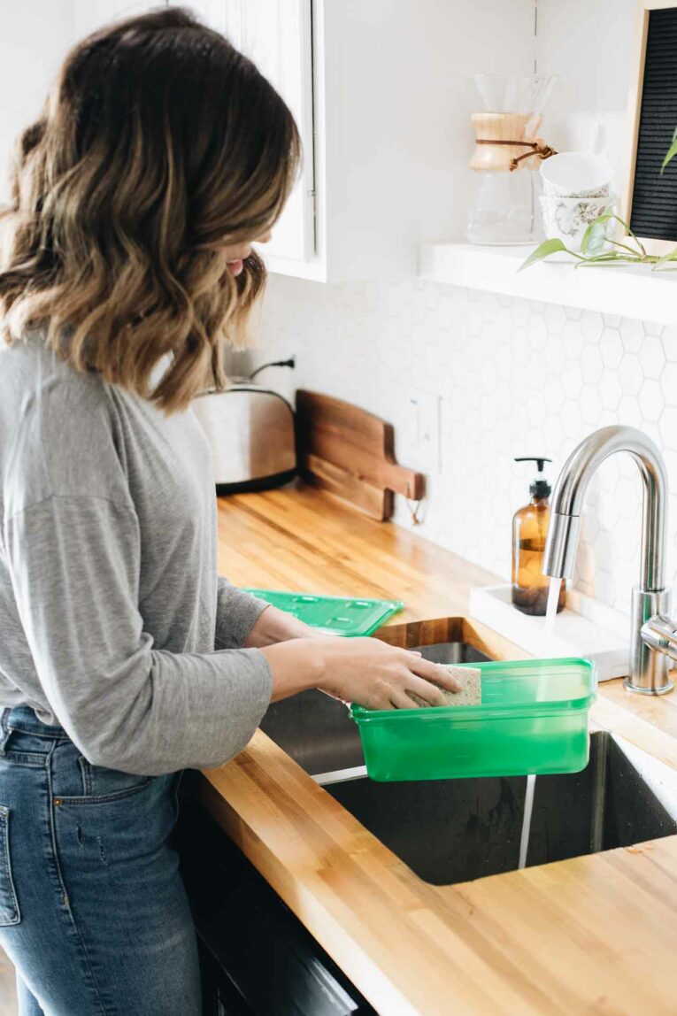 Woman washing Ziploc® brand holiday container for Thanksgiving leftovers.
