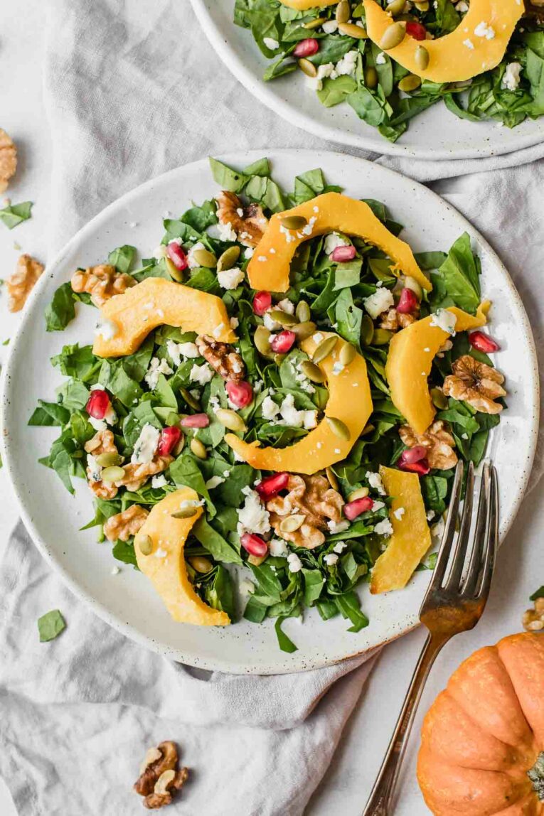 Roasted pumpkin salad on a white plate with a fork.