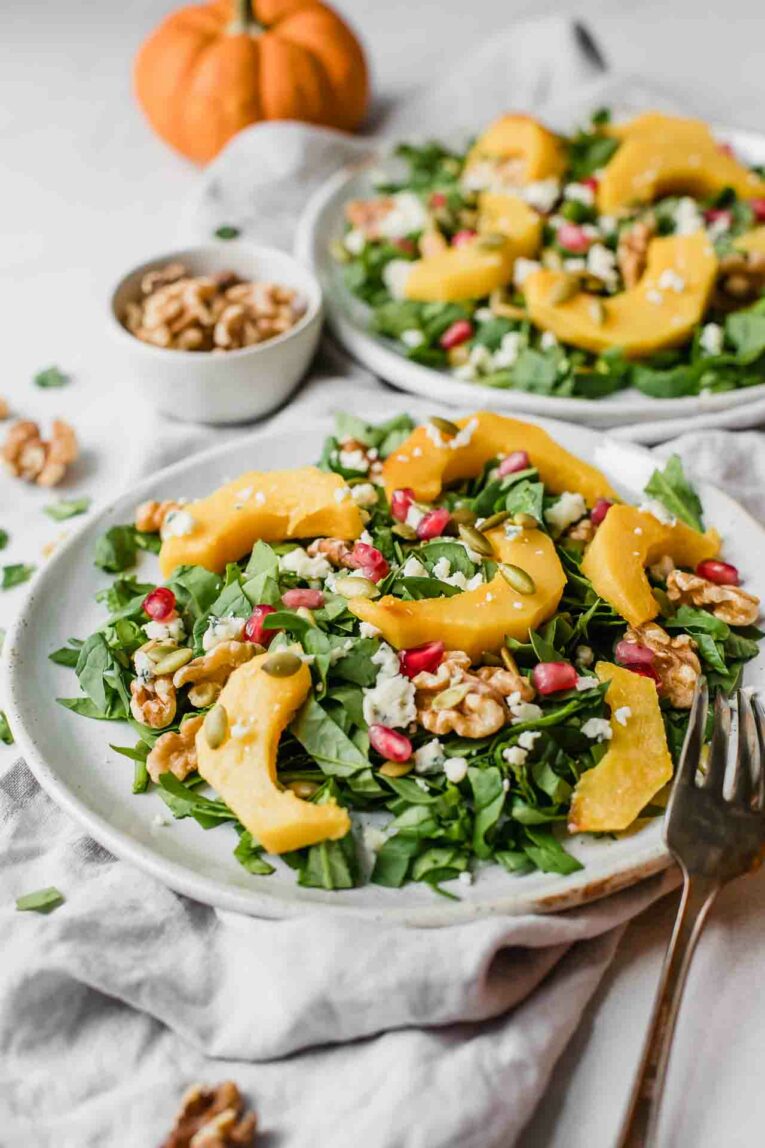 Angled shot of pumpkin salad on a white plate with a fork.